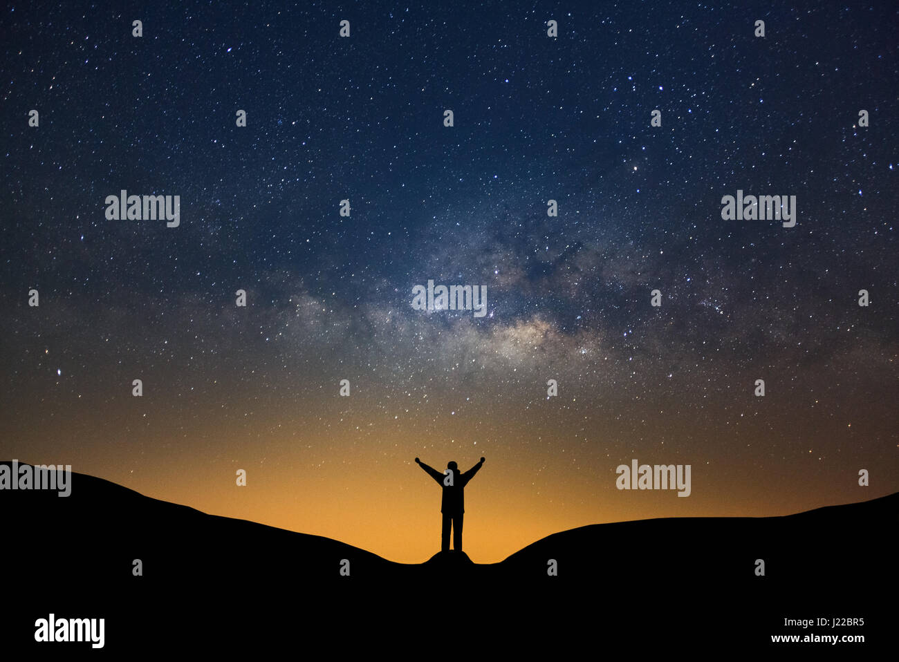 Milky way galaxy with stars and silhouette of a standing happy man ...