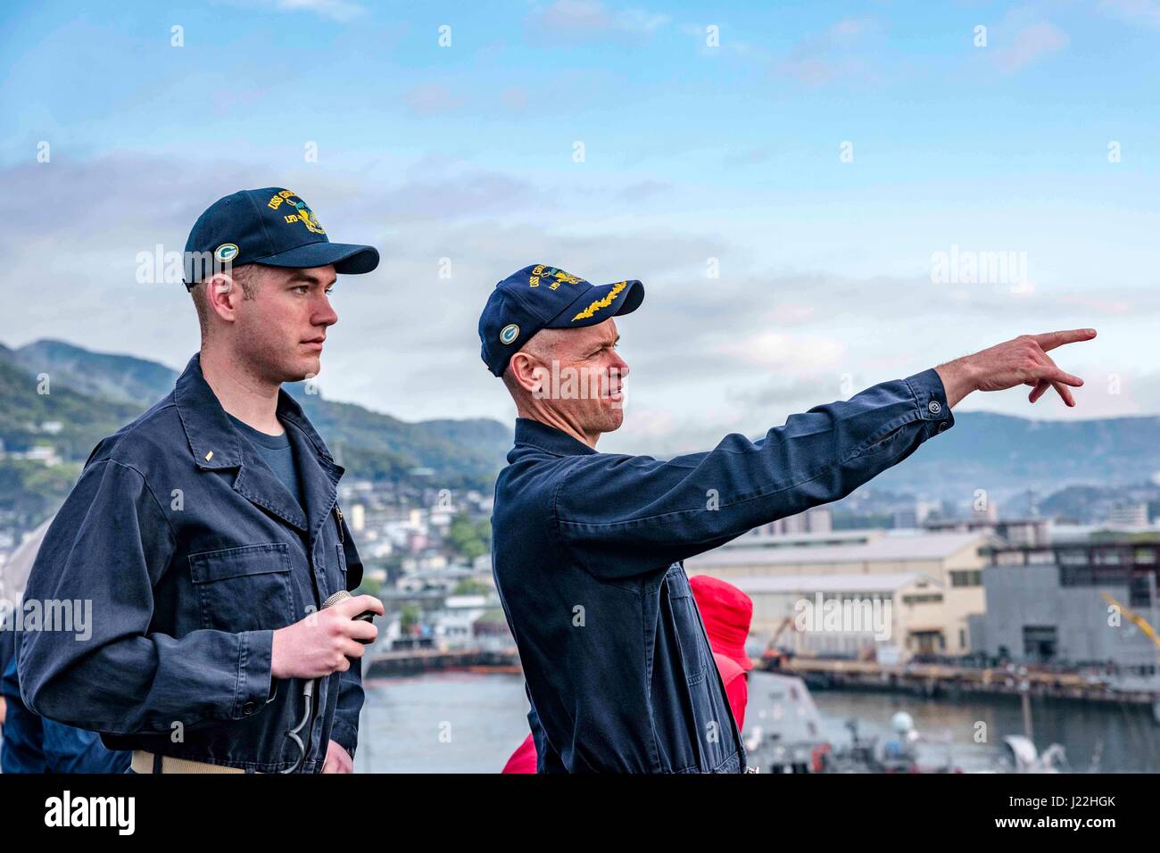 170418-N-JH293-008 SASEBO, Japan (April 18, 2017) Capt. Nathan Moyer, commanding officer of the amphibious transport dock USS Green Bay (LPD 20), points out the ship’s position to the conning officer, Ens. Zachary Fuller, as Green Bay departs Sasebo, Japan. Green Bay, assigned to Commander, Amphibious Squadron 11, is conducting at-sea preparations for its upcoming Mid-Cycle Inspection (MCI). MCI is conducted at the mid-year point prior to the Board of Inspection and Survey (INSURV) and is used to inspect and assess the material conditions of a ship. (U.S. Navy photo by Mass Communication Speci Stock Photo