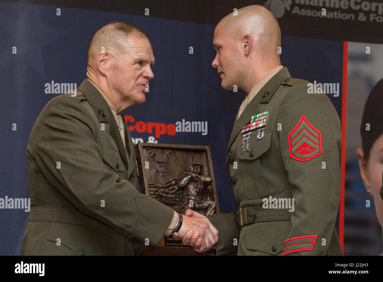 Commandant of the Marine Corps Gen. Robert B. Neller, left, shakes hands with Staff Sgt. Brandon W. Grzyb, recipient of the Pfc. Herbert Littleton Trophy for Staff Noncommissioned Officer Electronic Maintenance Excellence, during the 14th Annual C4 Awards Dinner Arlington, Va., April 20, 2017. While filling a billet normally held by a Chief Warrant Officer 2, Grzyb’s office was directly responsible for the readiness of 4,842 principle end items from 8th Communications Battalion, 2d Law Enforcement Battalion, 2d Expeditionary Operations Training Group, II MEF Headquarters, and II MEF Command El Stock Photo