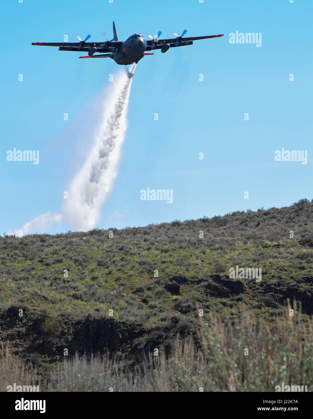 A C130h aircraft loaded with the MAFFS (Modular Airborne Fire Fighting System) from the 152rd Airlift Wing of Reno, Nevada drops a water line while training to contain wildfires just outside Bosie, Idaho. April 21, 2017. More than 400 personnel of four C-130 Guard and Reserve units — from California, Colorado, Nevada and Wyoming, making up the Air Expeditionary Group — are in Boise, Idaho for the week-long wildfire training and certification sponsored by the U.S. (U.S. Air National Guard photo by Staff Sgt. Nieko Carzis) Stock Photo