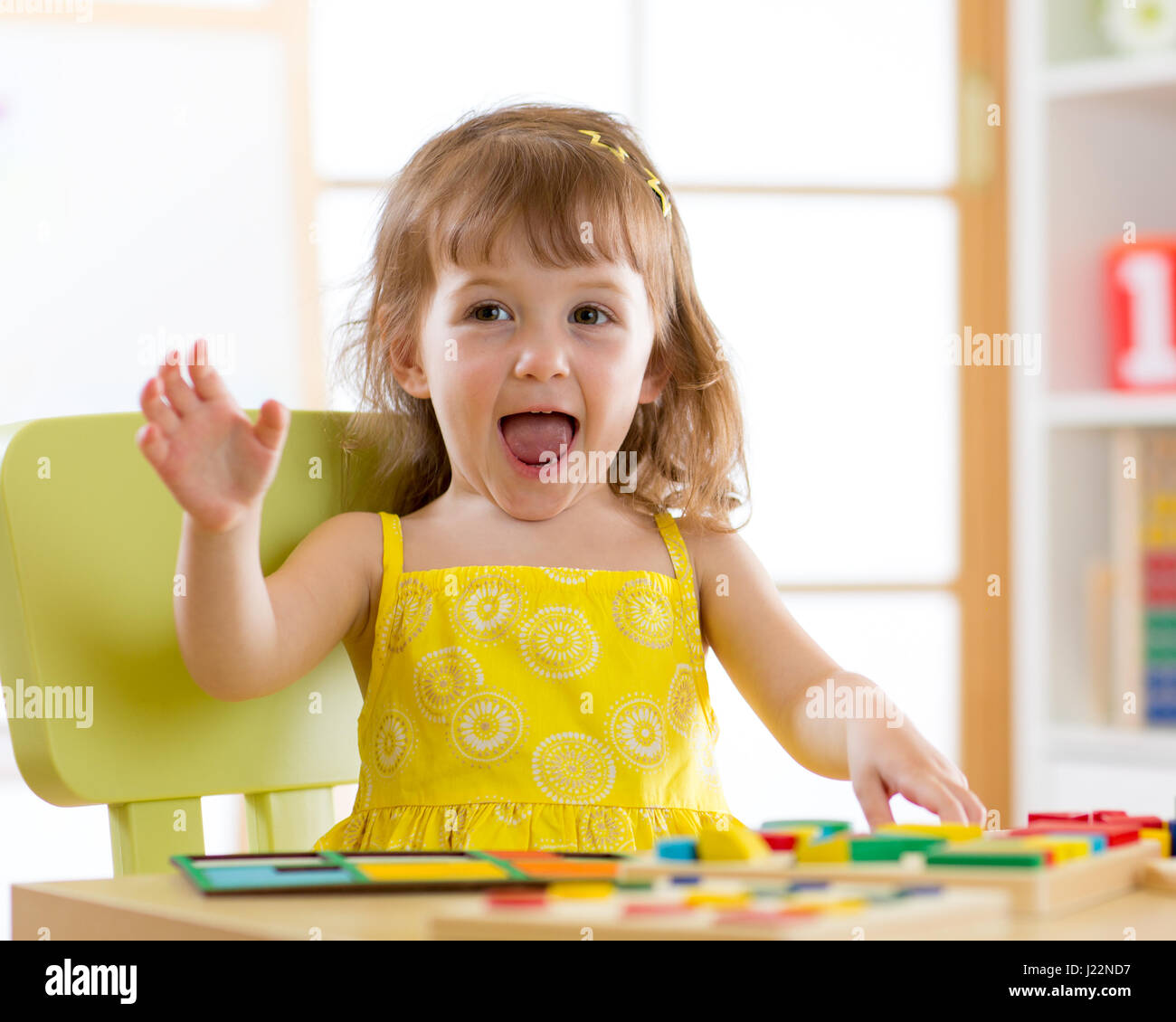 Little girl kid playing with logical toys. Child sorting and arranging colors and forms Stock