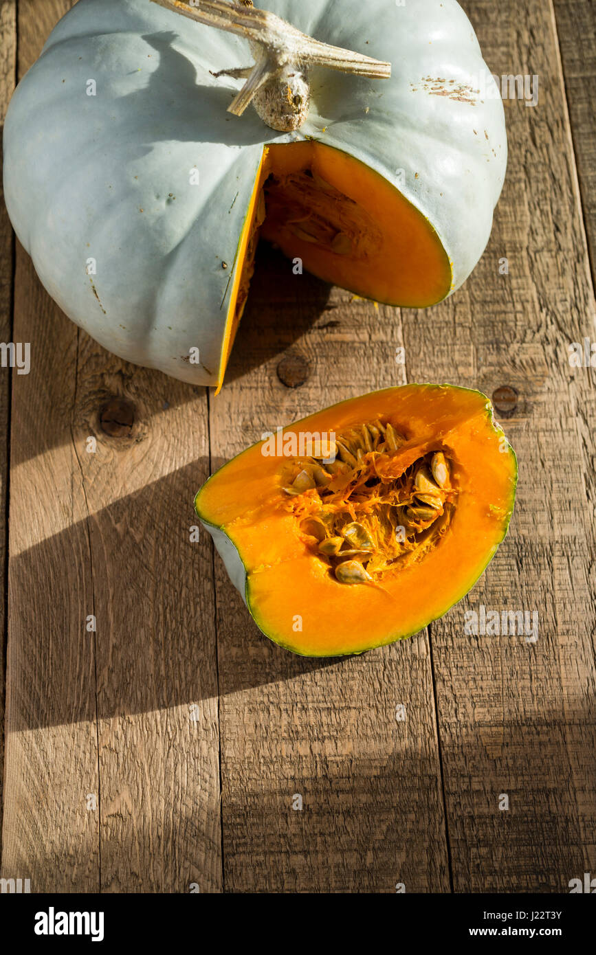 A Crown Prince Squash being cut and prepared for cooking on a wooden table. Stock Photo