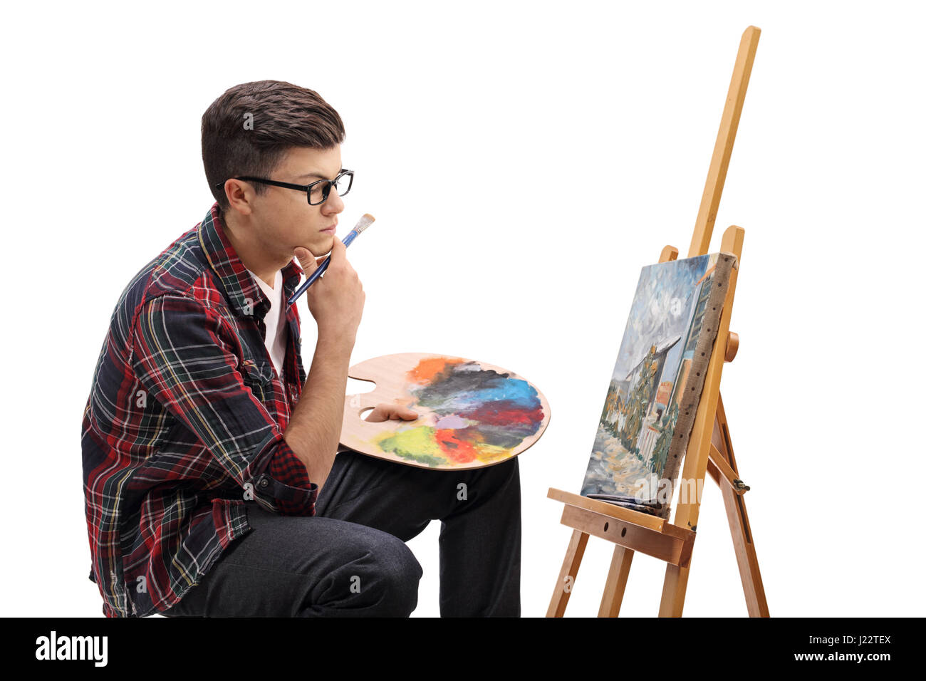 Profile shot of a pensive teenage painter looking at a painting