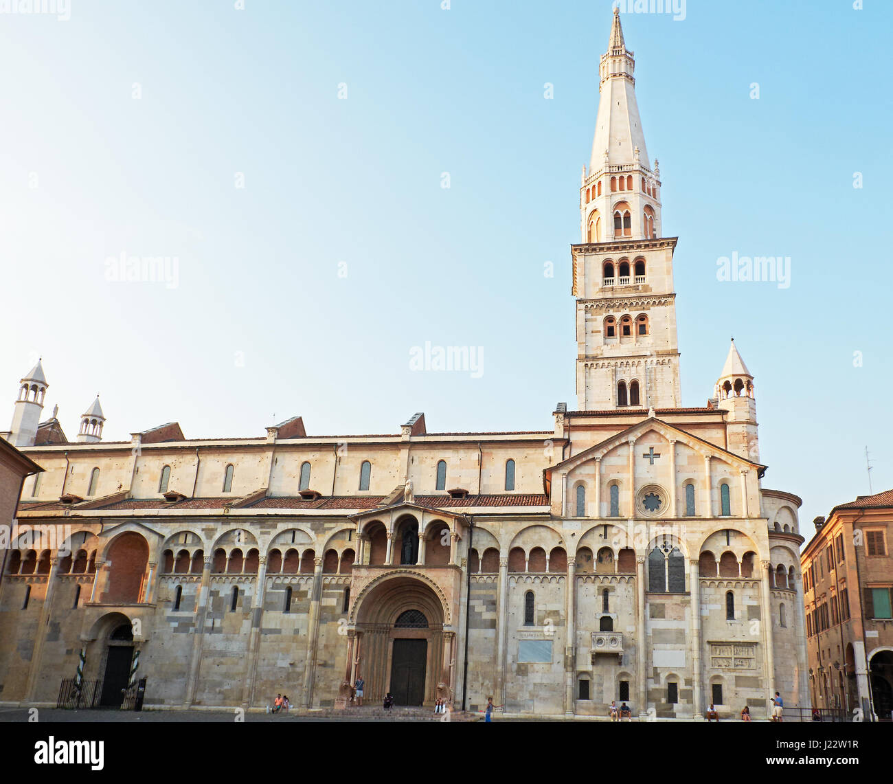 People in front of Metropolitan Cathedral of Santa Maria Assunta e San Geminiano in Piazza Grande of Modena at sunset. Italy Stock Photo