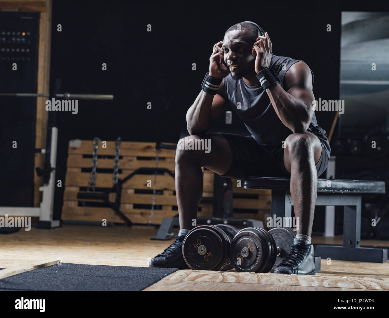 Athlete sitting in gym, wearing headphones, concentrating Stock Photo