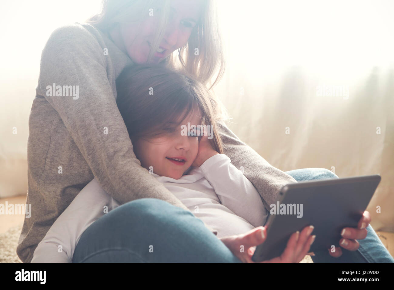 Mother and little daughter using tablet at home Stock Photo