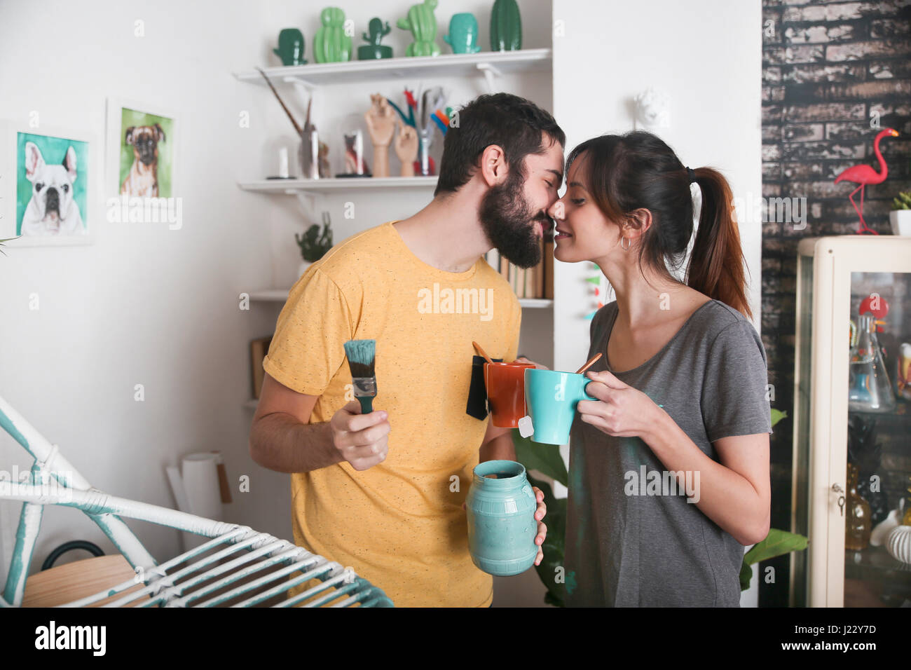 Young couple kissing between paintbrushes and tea mugs Stock Photo