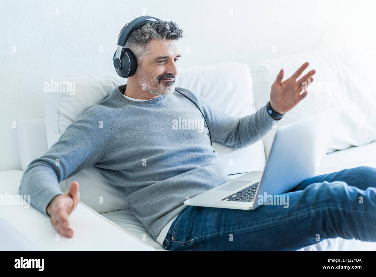 Mature man at home using laptop and wearing headphones Stock Photo - Alamy