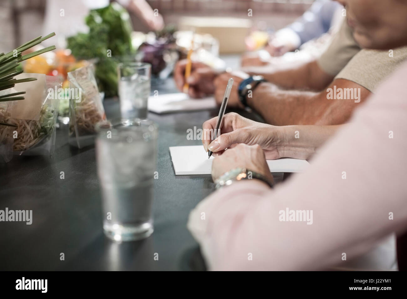 People writing down notes in cooking class Stock Photo