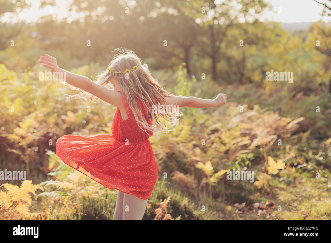 Little girl wearing red summer dress dancing in nature Stock Photo