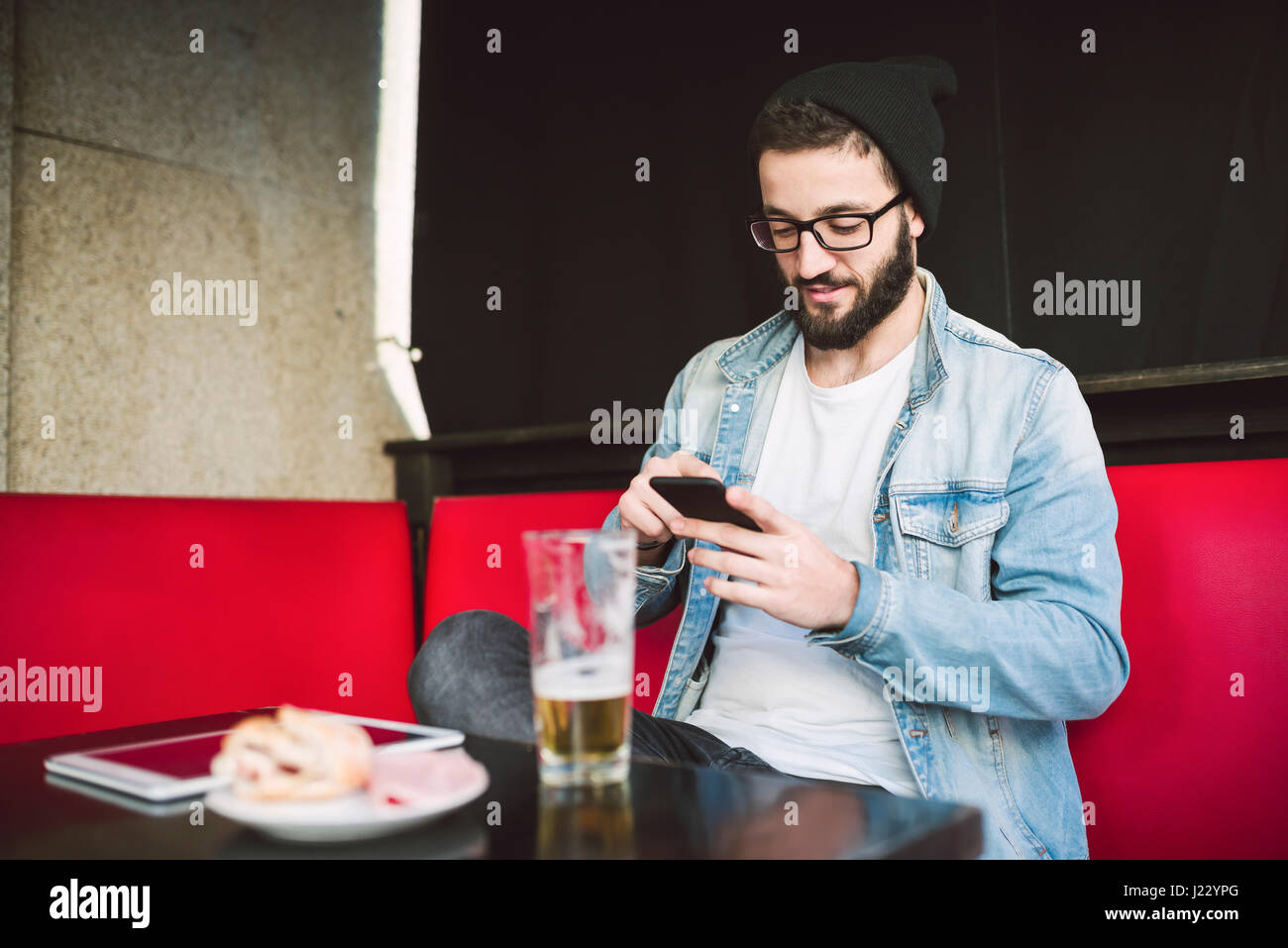 Young man sitting in a pub checking messages Stock Photo