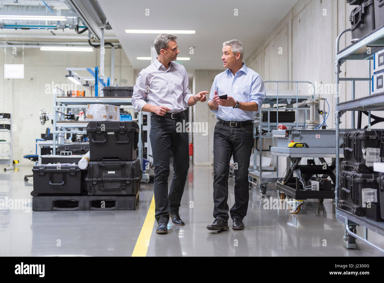 Two businessmen walking in factory hall Stock Photo - Alamy