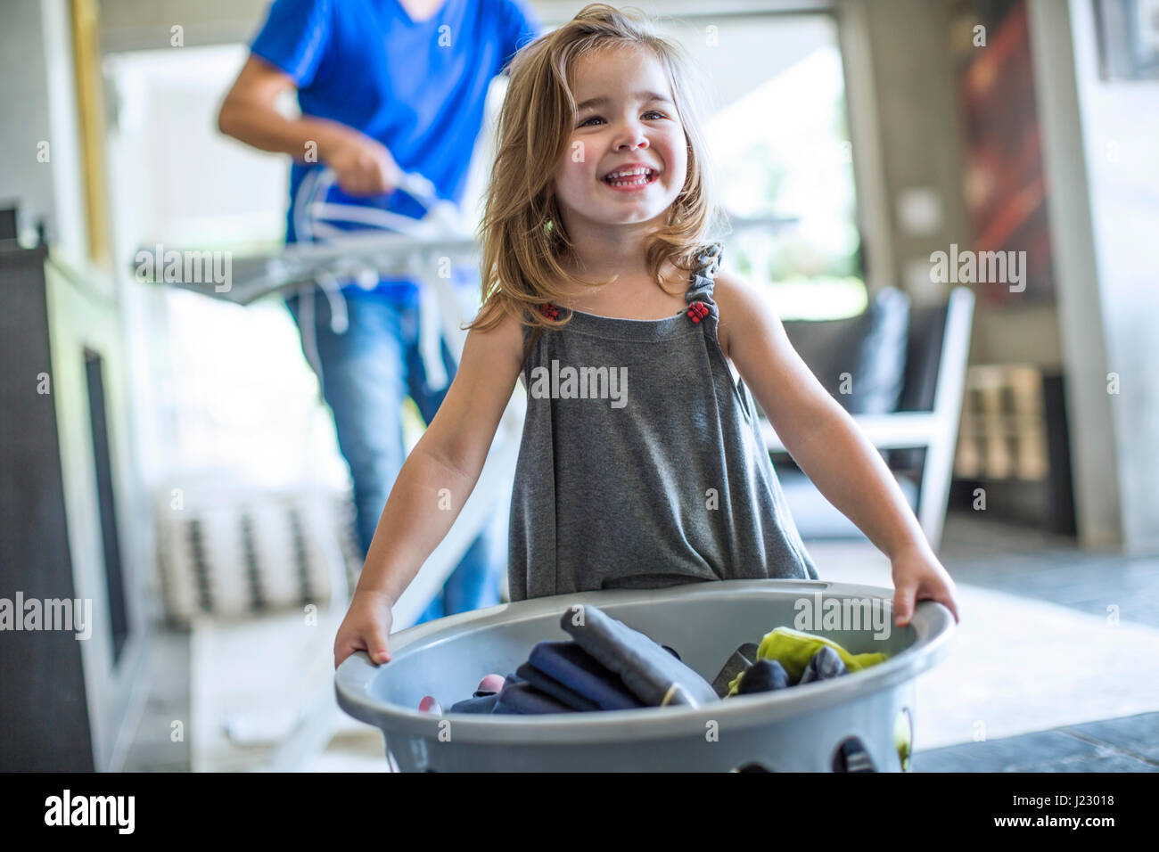 Happy baby girl holding laundry basket Stock Photo - Alamy