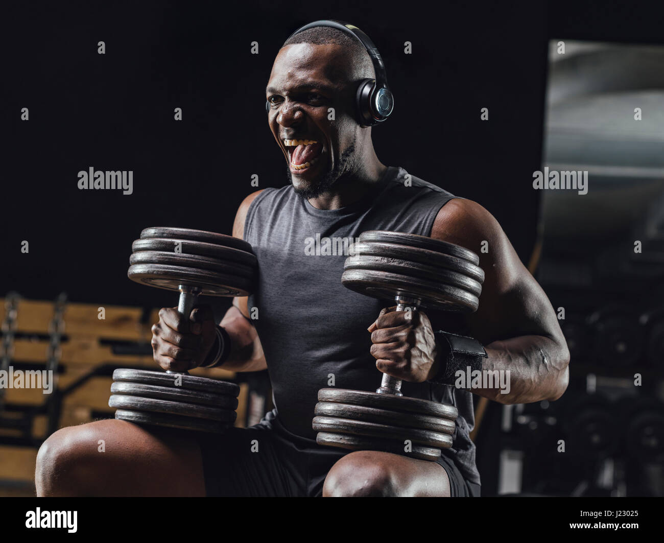 Athlete training with dumbbells in gym, screaming Stock Photo