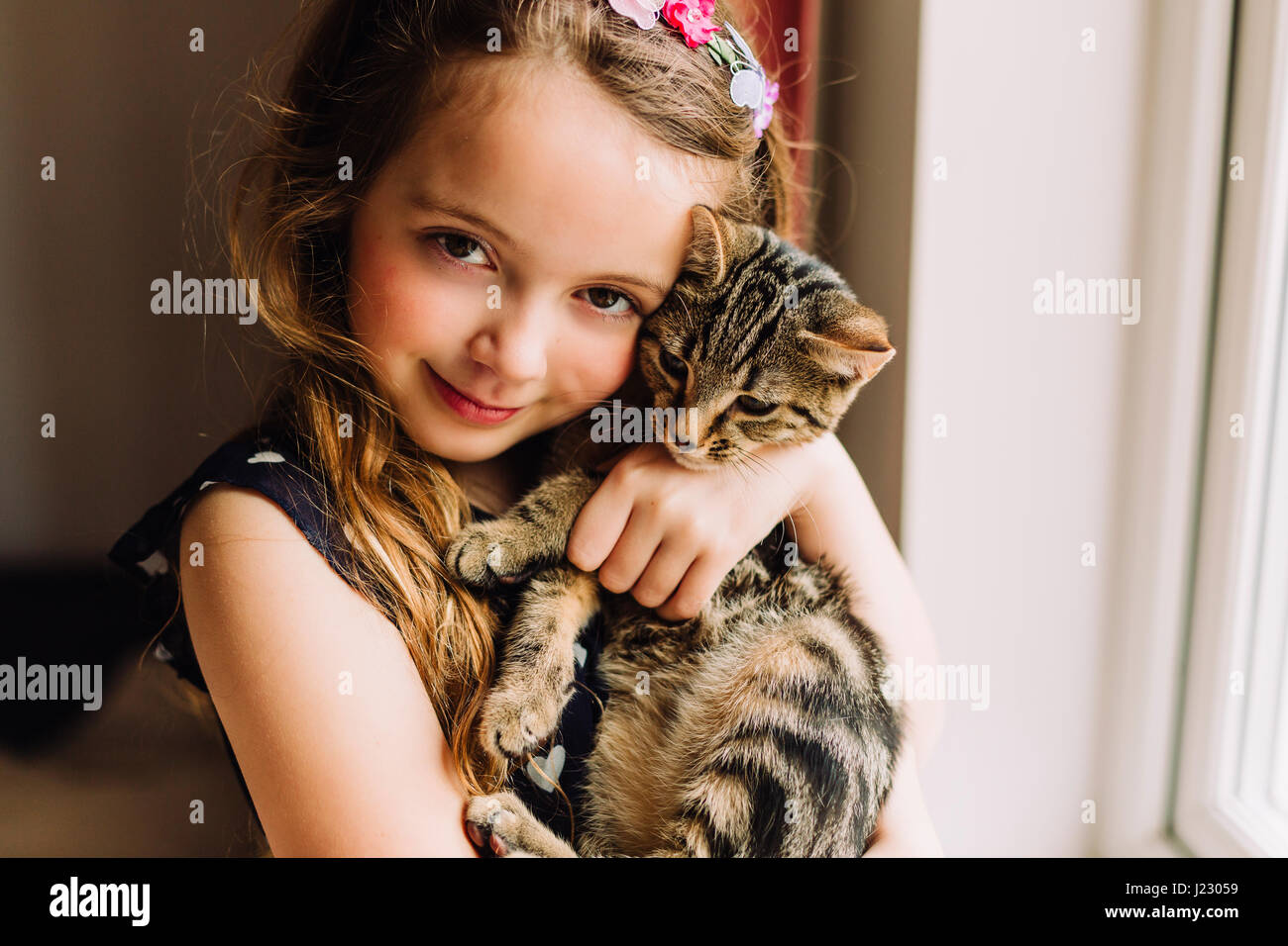 Portrait of little girl holding tabby kitten Stock Photo