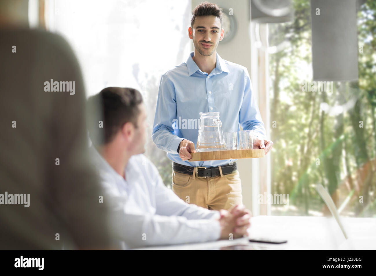 Young man serving water at a business meeting Stock Photo Alamy
