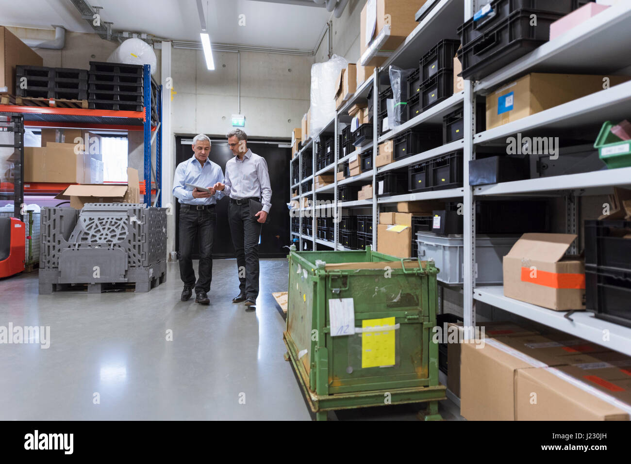 Two businessmen walking in factory hall Stock Photo - Alamy