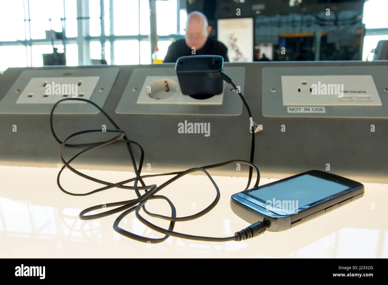 Phone charging on a table at charging station in the lobby. Free