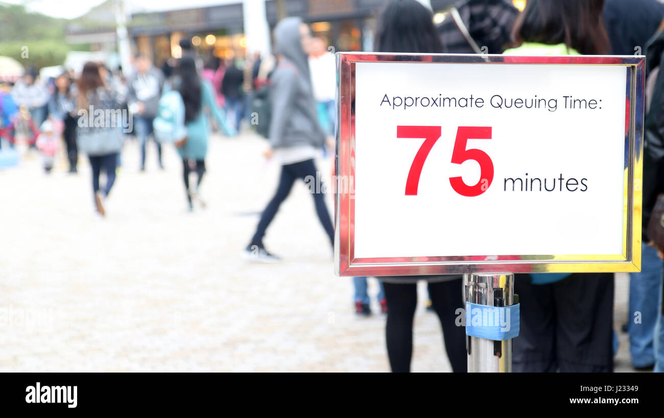 People waiting in a long queue, focus on the information sign