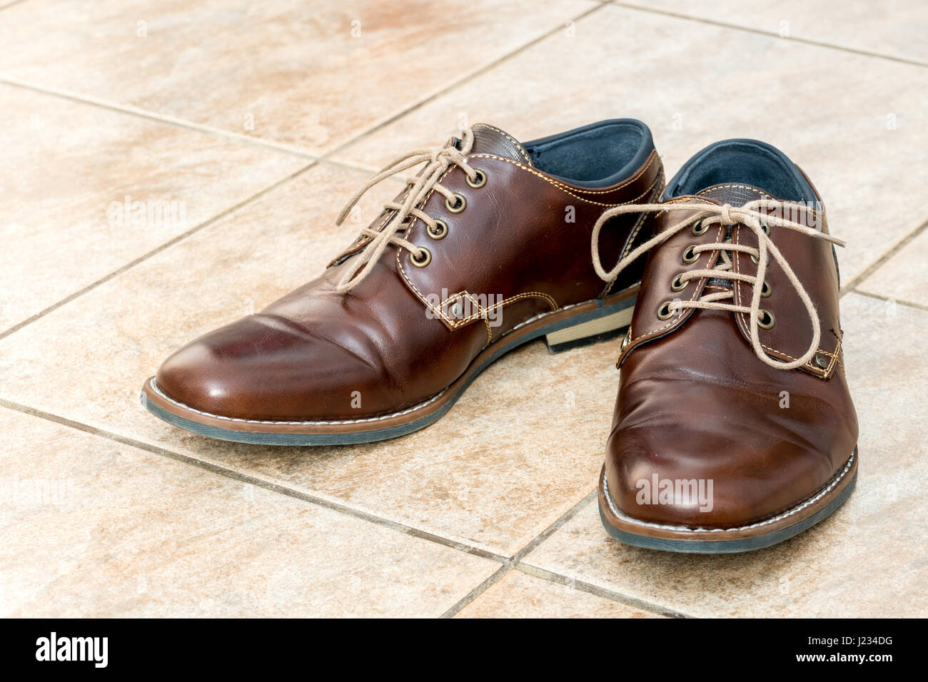 Fashion brown leather men's shoes on a light brown ceramic tiles Stock Photo