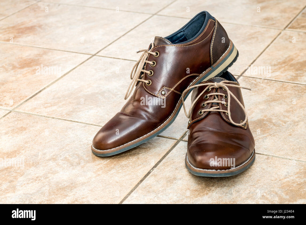 Pair of fashion brown men's shoes with shoestring on a light brown ceramic tiles Stock Photo