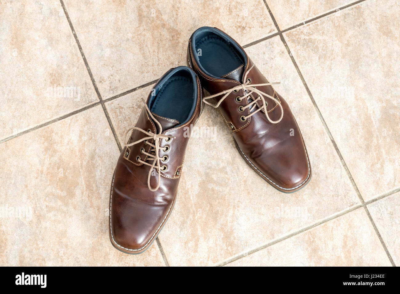 Fashion brown men's shoes on a light brown ceramic tiles, view from above Stock Photo