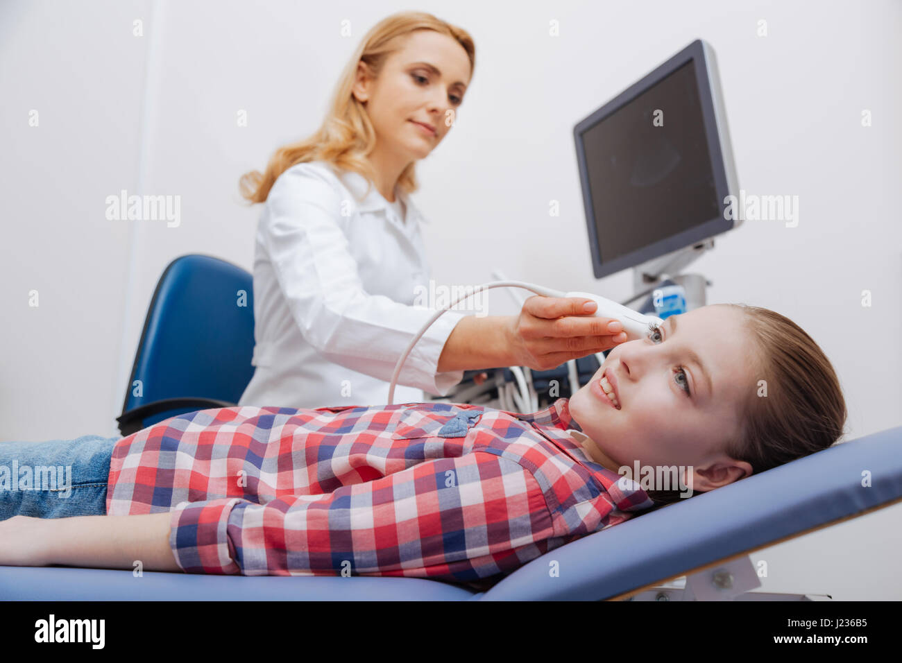 Confident medical specialist providing ultrasonic head scanning at work Stock Photo