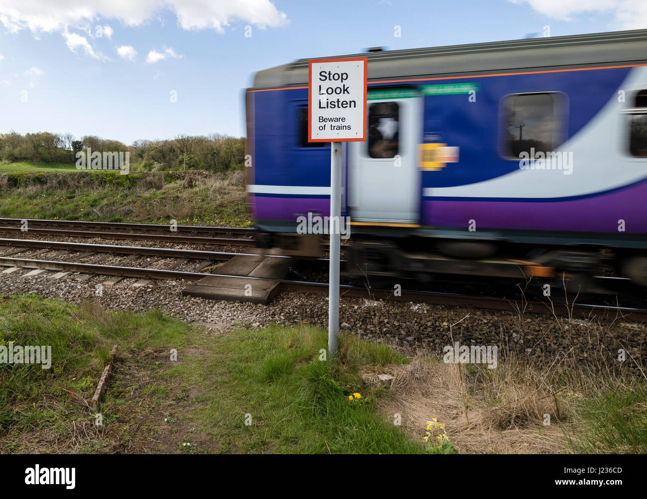 Train Passing a Pedestrian Crossing Warning Sign, Silverdale Lancashire, North West, England UK Stock Photo