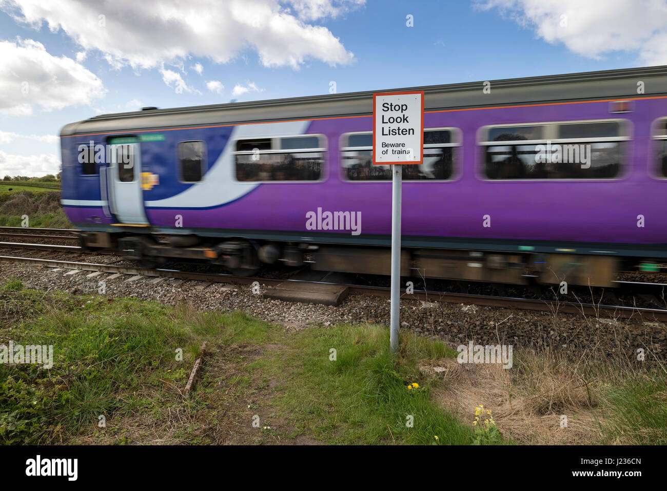 Train Passing a Pedestrian Crossing Warning Sign, Silverdale Lancashire, North West, England UK Stock Photo