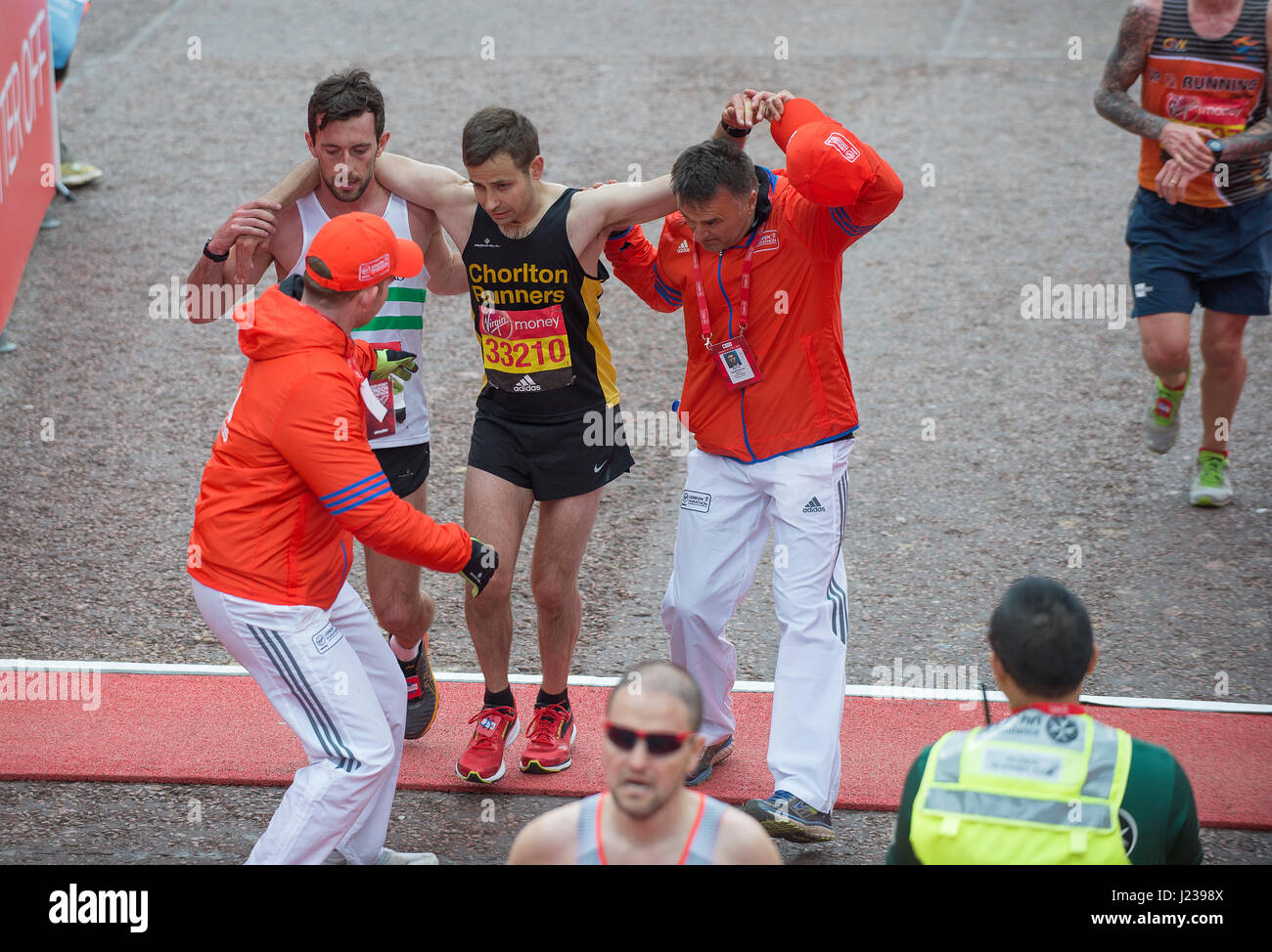 Help for a runner crossing the finish line with jelly legs, 2017 Virgin Money London Marathon. Credit: Malcolm Park/Alamy. Stock Photo