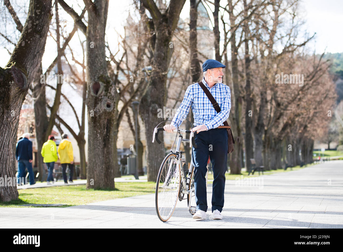 Senior man in blue checked shirt with bicycle in town. Stock Photo