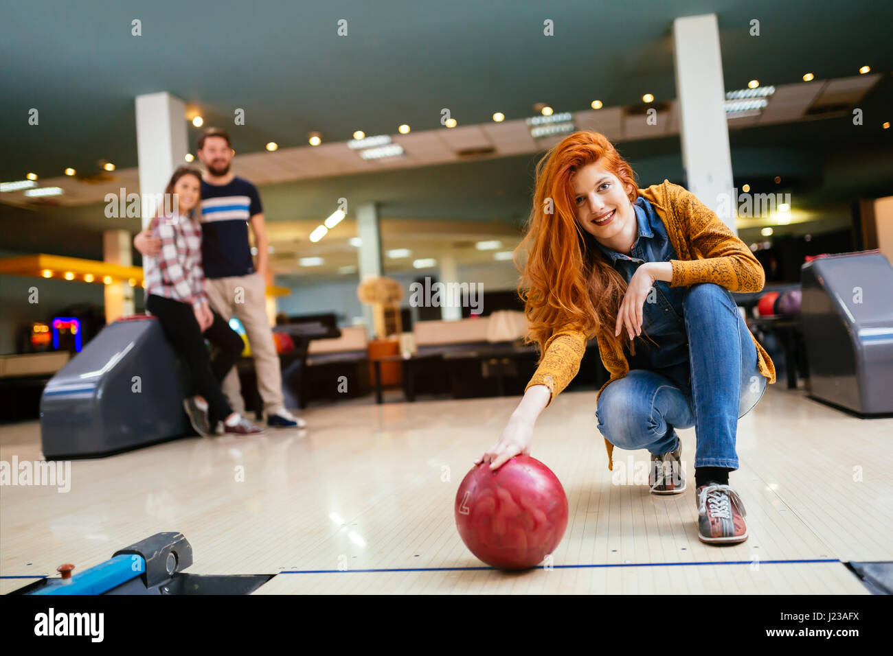 Beautiful woman bowling with friends getting ready to throw ball Stock