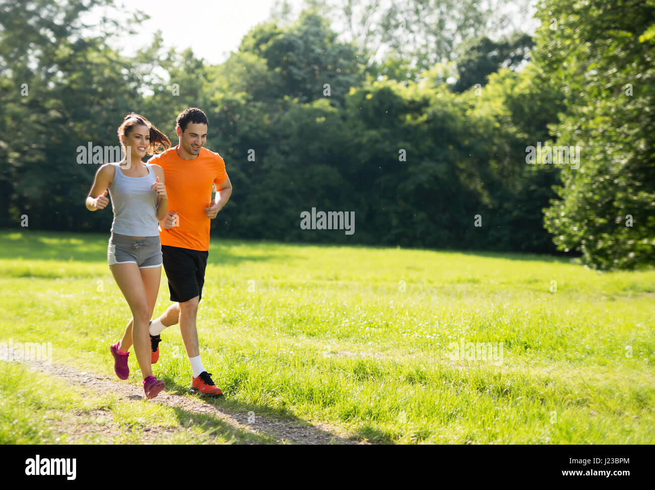 Happy couple running and jogging together in nature Stock Photo - Alamy