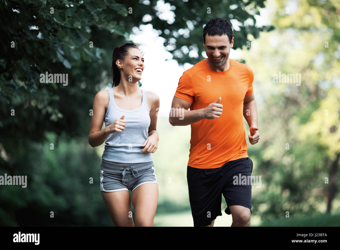 Happy couple running and jogging together in nature Stock Photo - Alamy