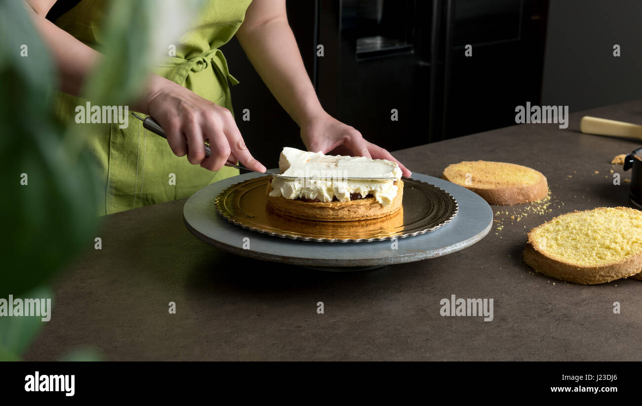 Woman decorating a delicious cake with icing cream Stock Photo