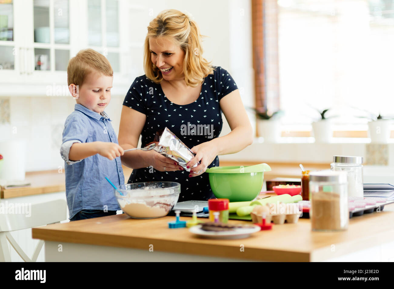 Child Helping In Kitchen Child helping mother prepare muffins in kitchen Stock Photo - Alamy