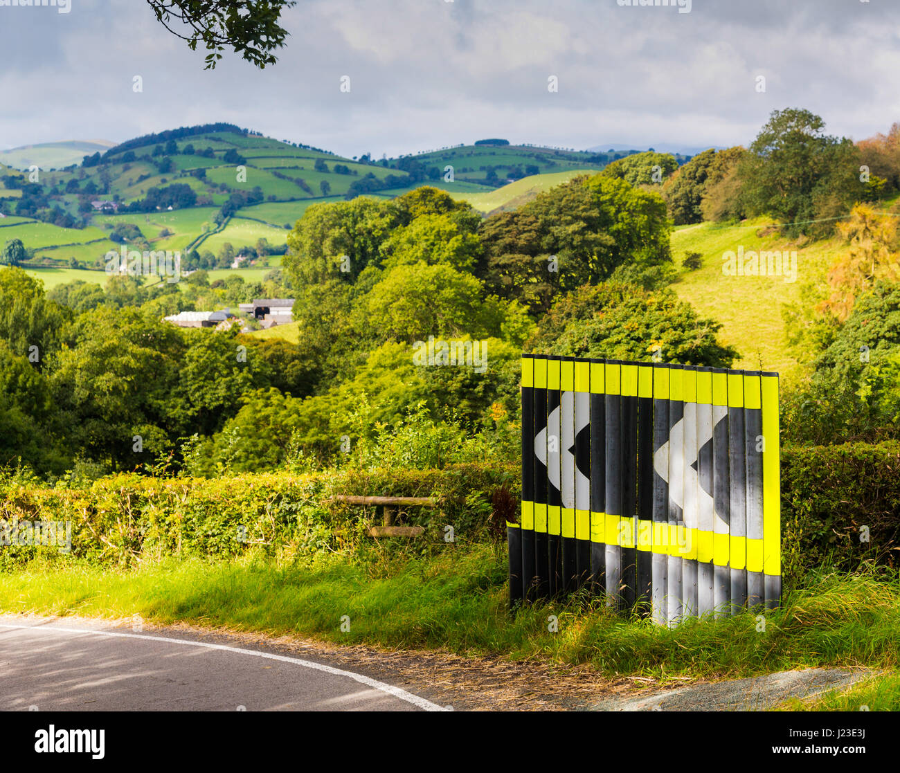 Dangerous bend warning sign in road with arrow signs in rolling countryside, UK Stock Photo