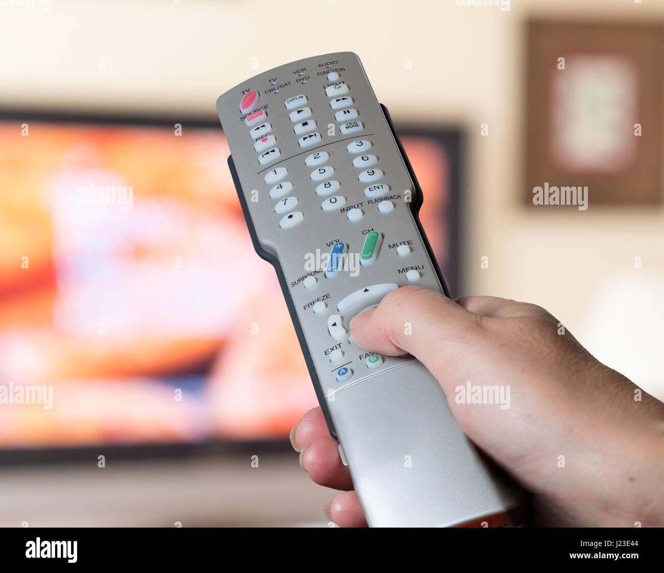 Hand holding and using a TV remote control to change channels, channel hopping Stock Photo