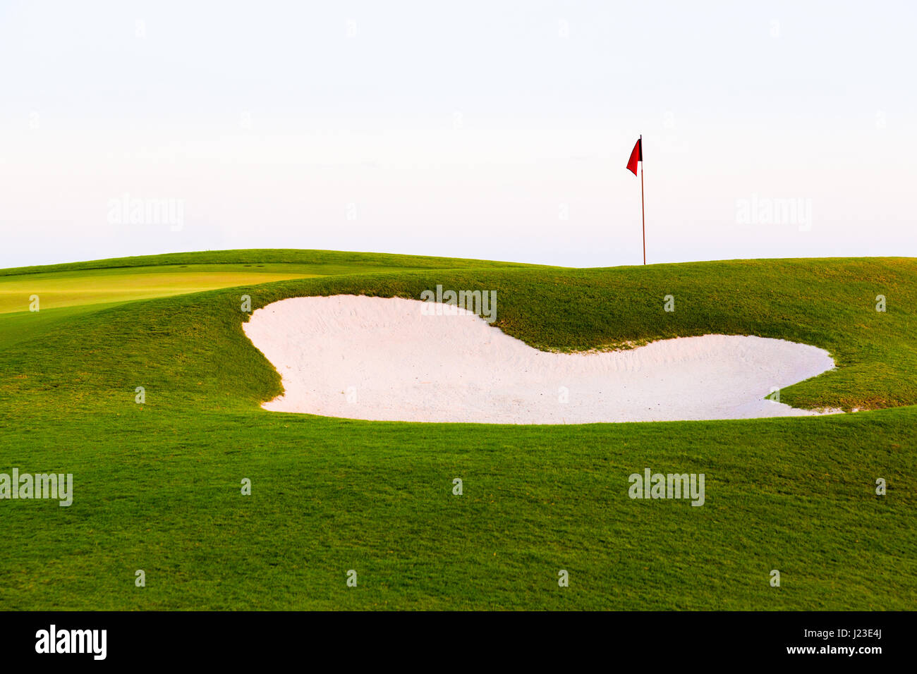 Red flag of golf hole above sand trap or golf course bunker Stock Photo