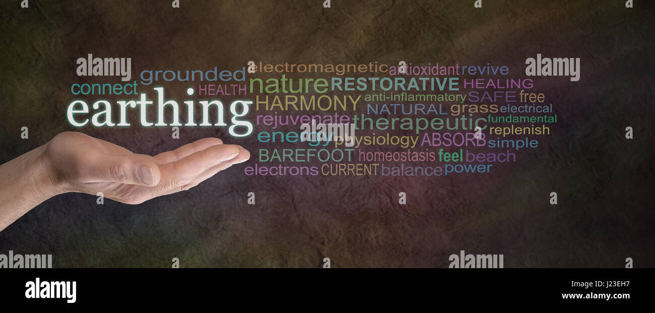 Earthing Word Cloud - male hand outstretched with the word EARTHING floating above surrounded by a word cloud on a dark rustic stone background Stock Photo