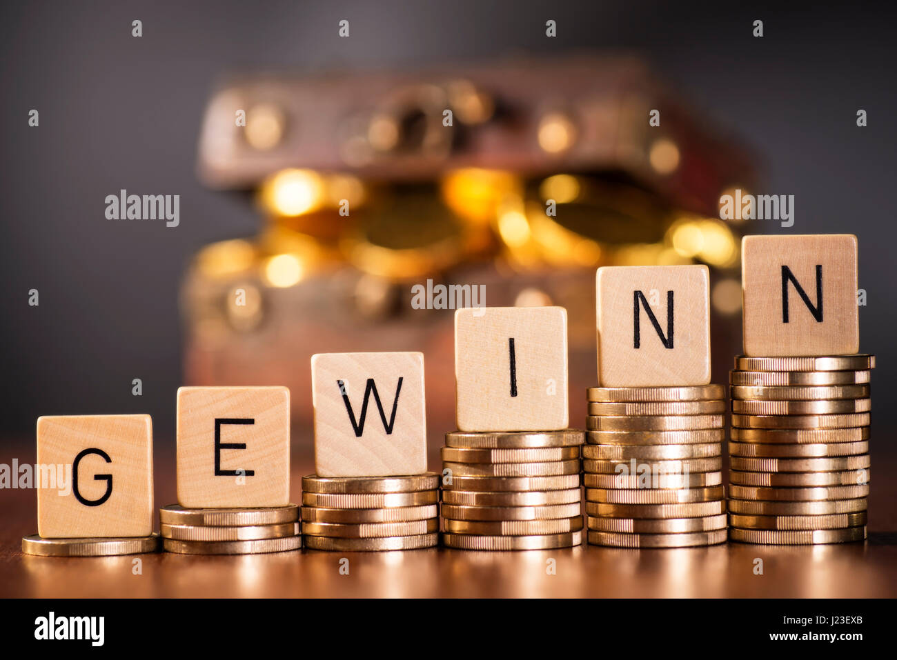 Stack of coins and the word profit in front of a treasure chest. Stock Photo