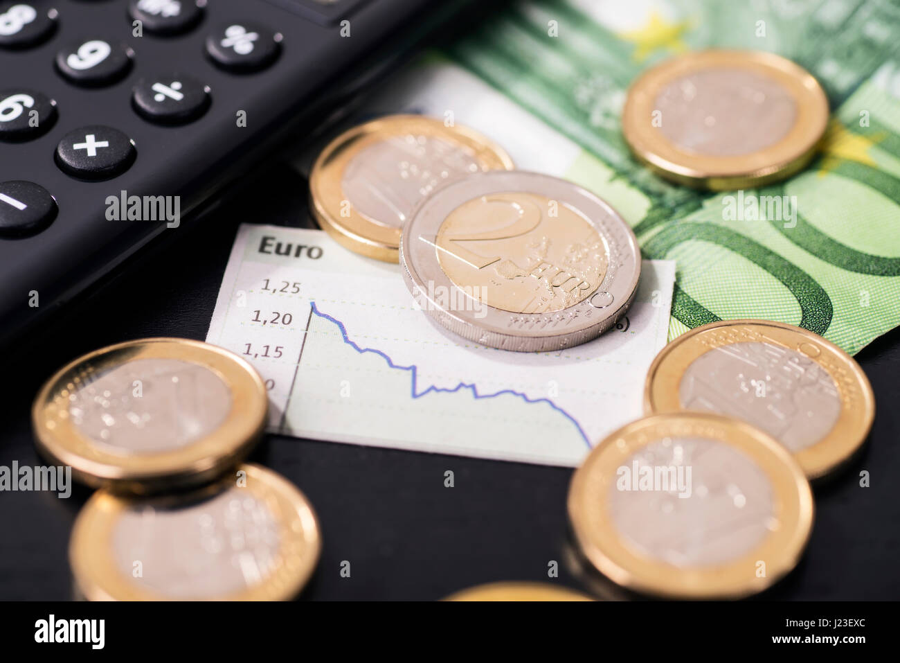 A graphic shows the falling euro rate and is surrounded by euro coins. Stock Photo