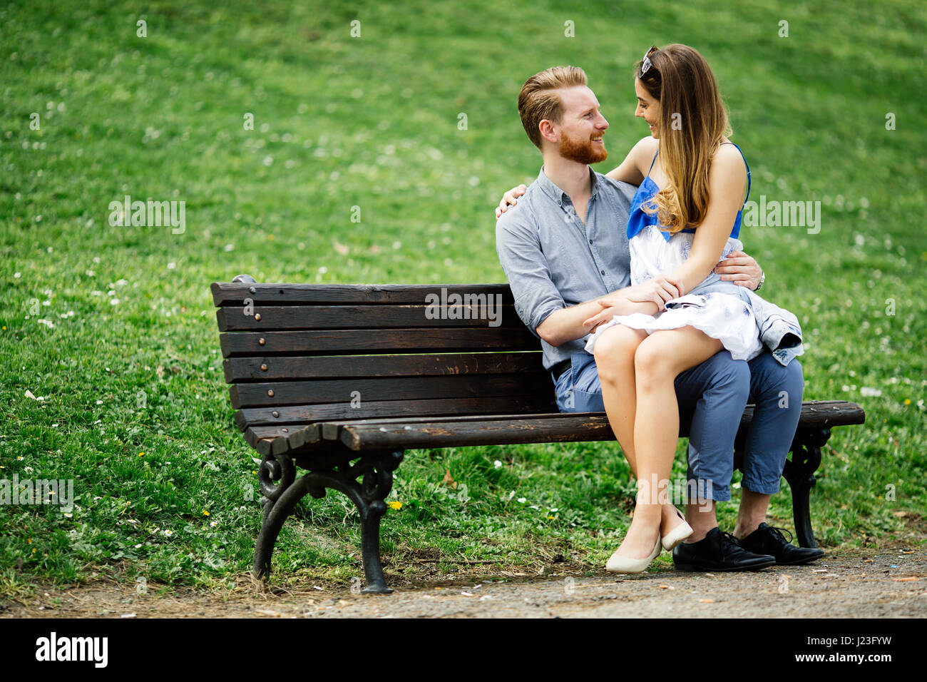 Romantic couple in park sitting on bench Stock Photo - Alamy