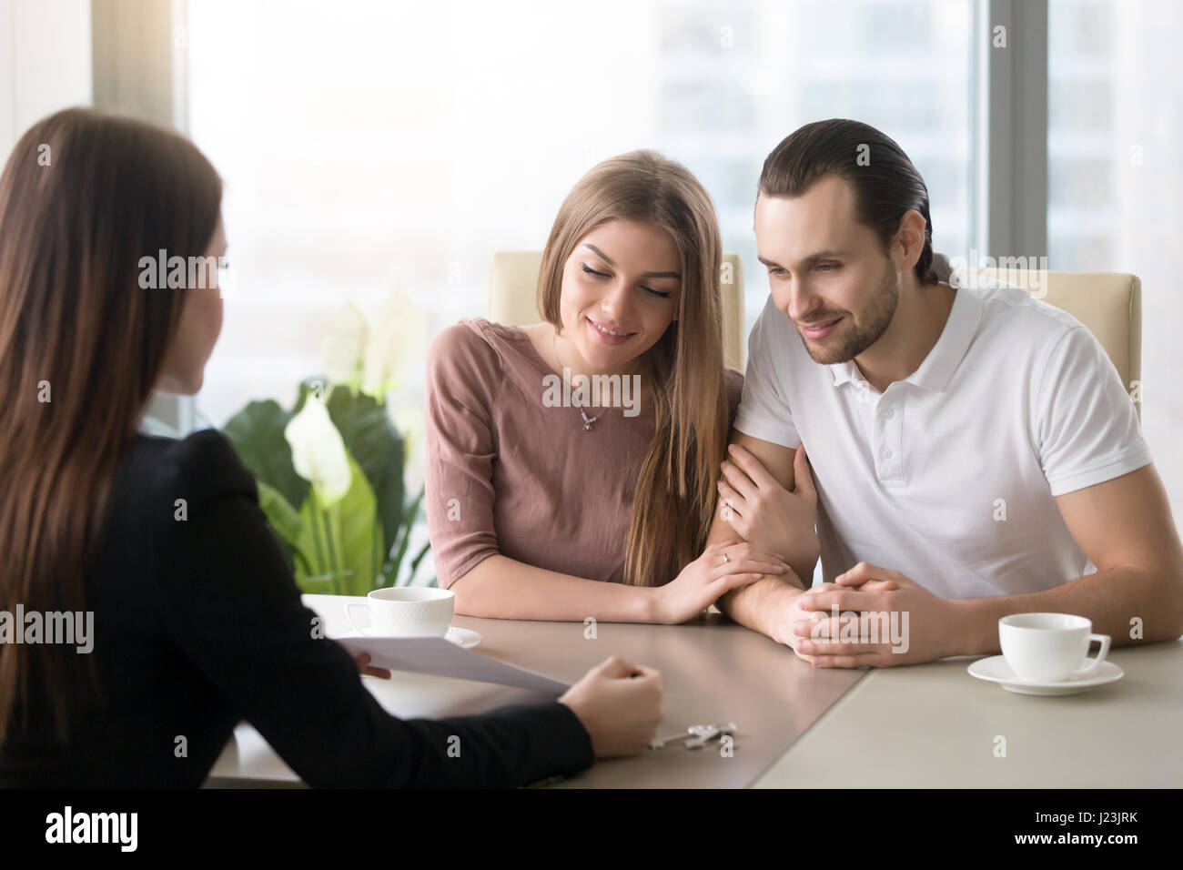 Young couple in real estate agency office meeting with agent Stock Photo
