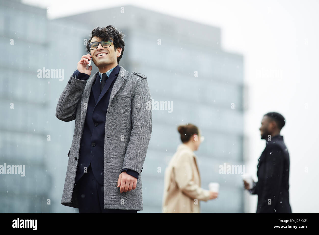 Businessman with mobile telephone calling on background of two co ...