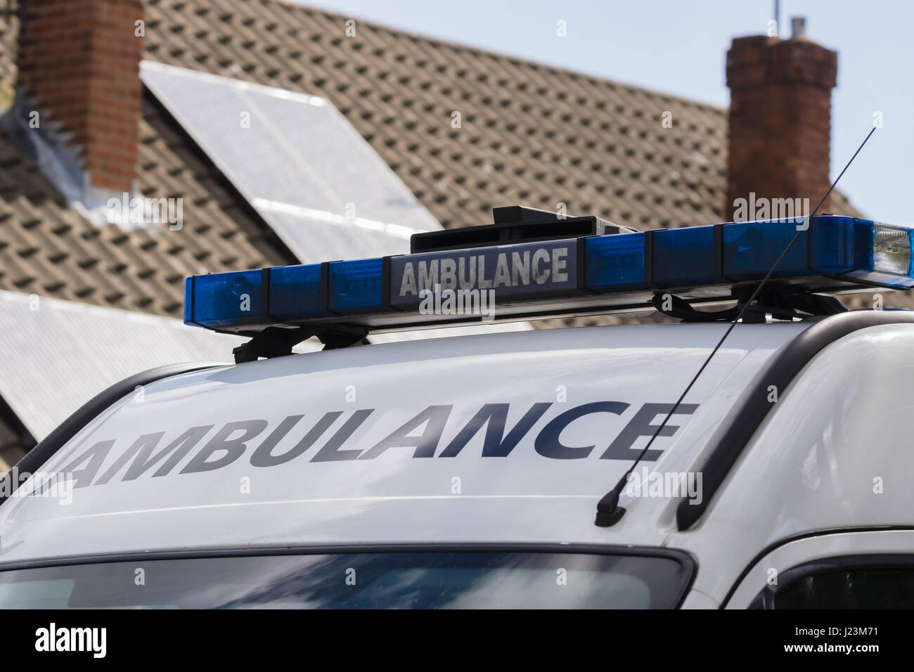Light bars on unidentified British ambulance attending a medical emergency outside a house Stock Photo