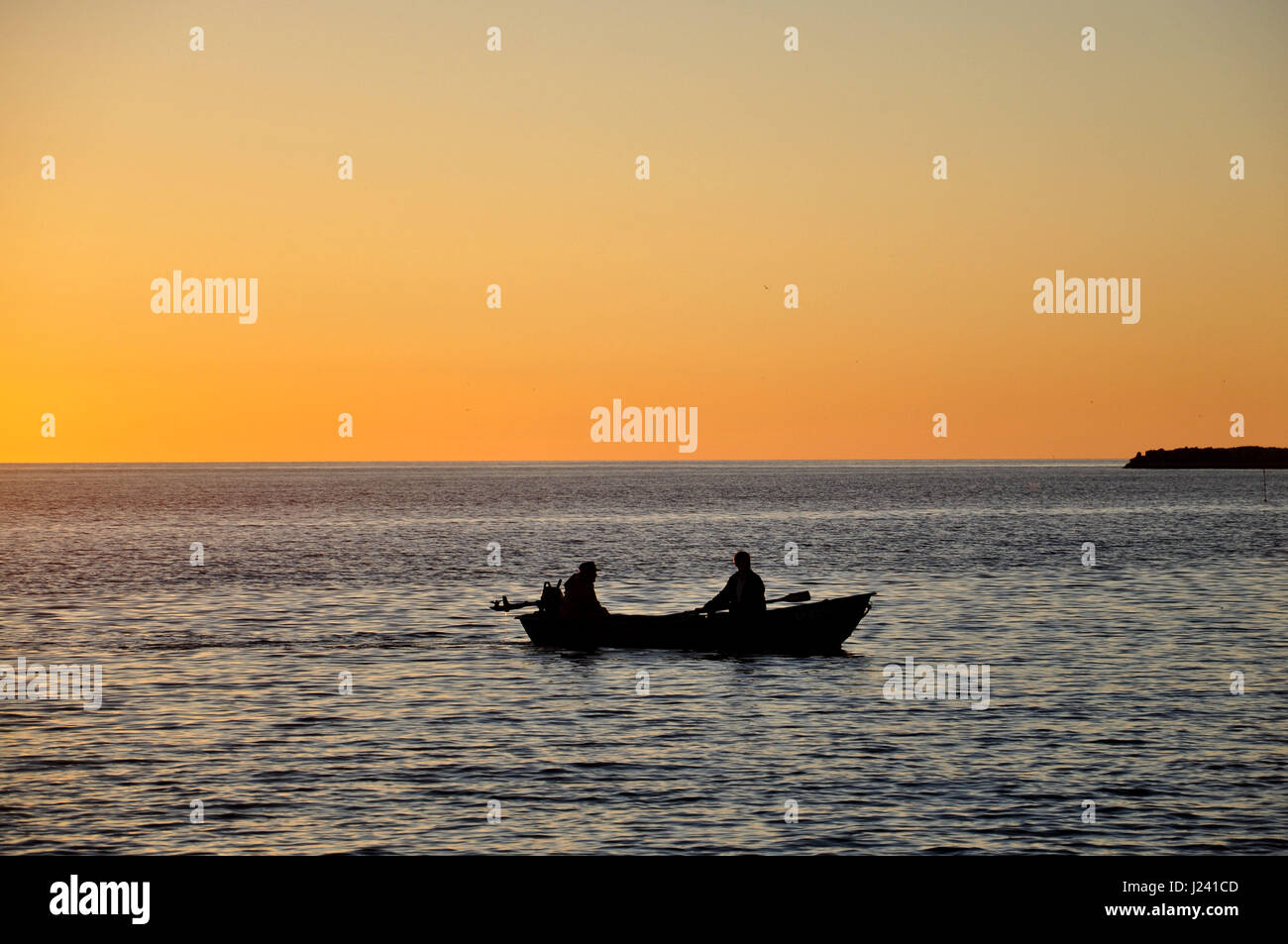 The boat with the fishermen in the sea at sunset Stock Photo - Alamy