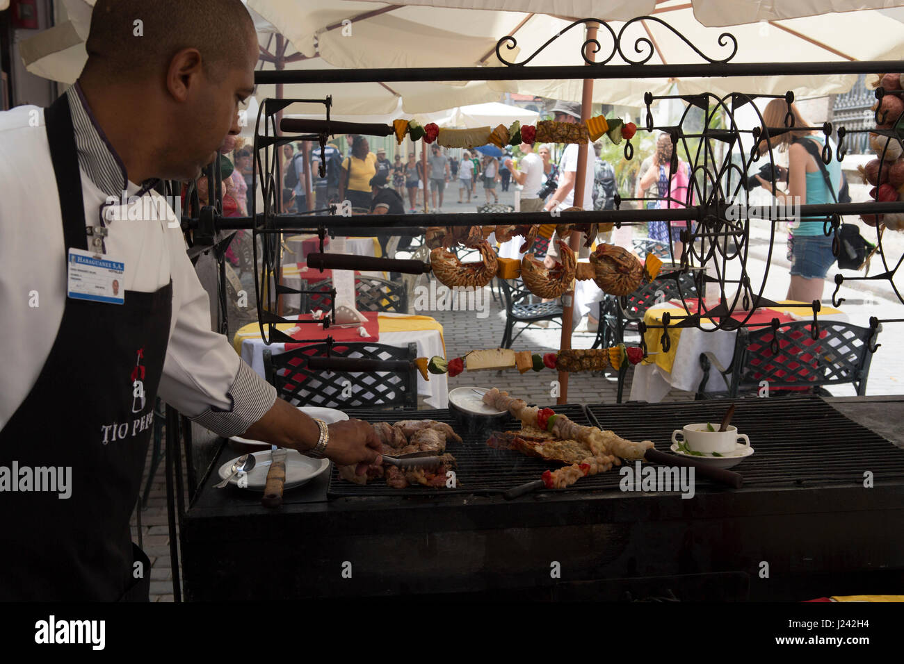 Chef at outdoor restaurant with food on a grill. Stock Photo