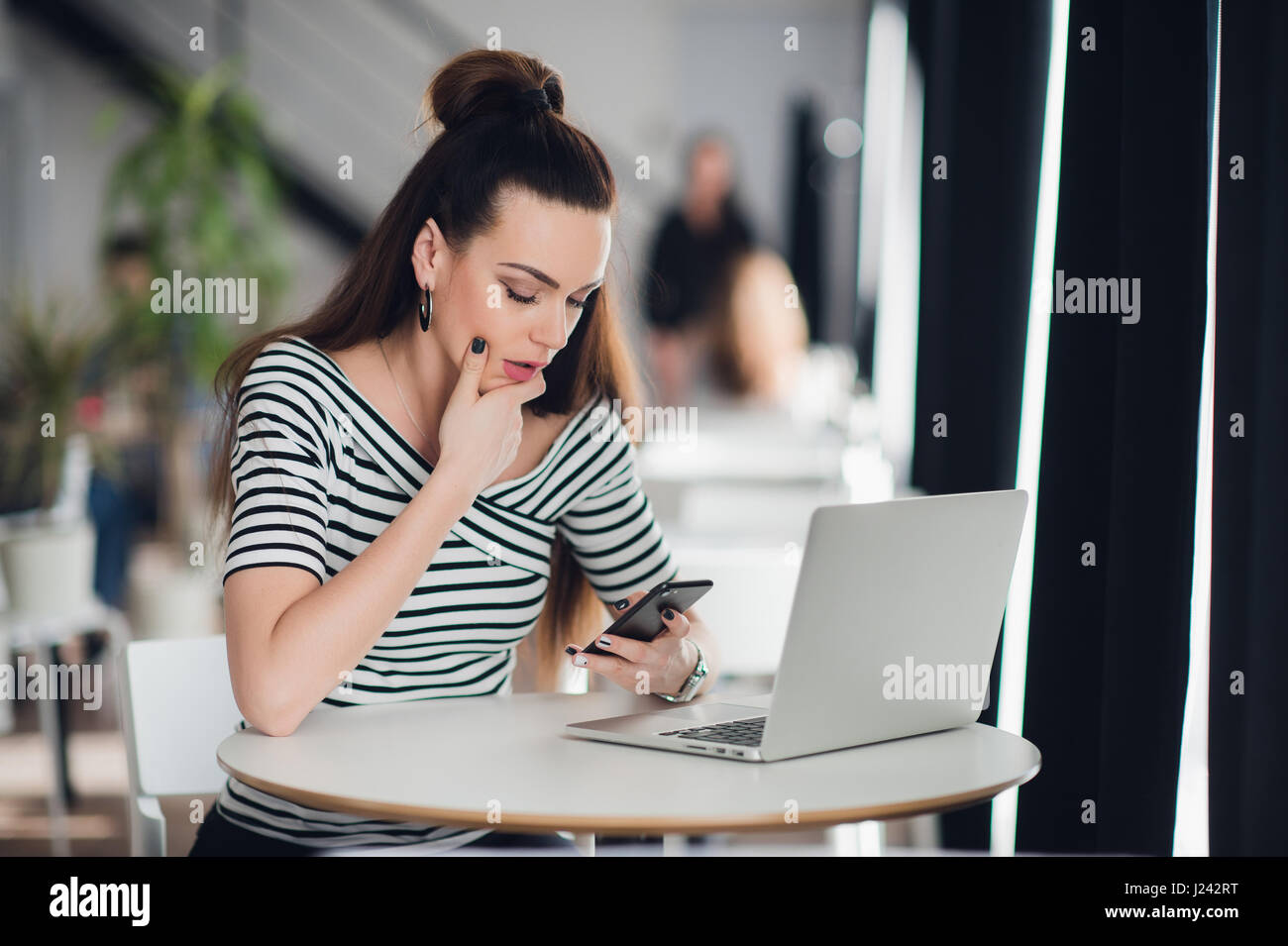 Worried executive talking on the phone trying to solve problems with multiple devices sitting in a desktop at cafe. Stock Photo