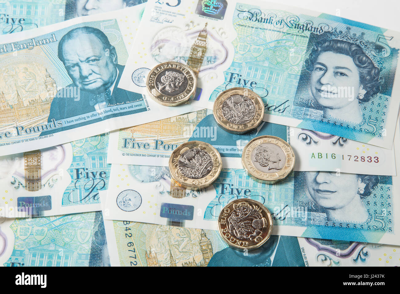 New British £1 Coins on a background of UK £5 pound notes Stock Photo